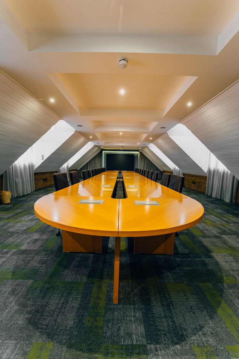 Long polished cherrywood boardroom under pitched ceiling
