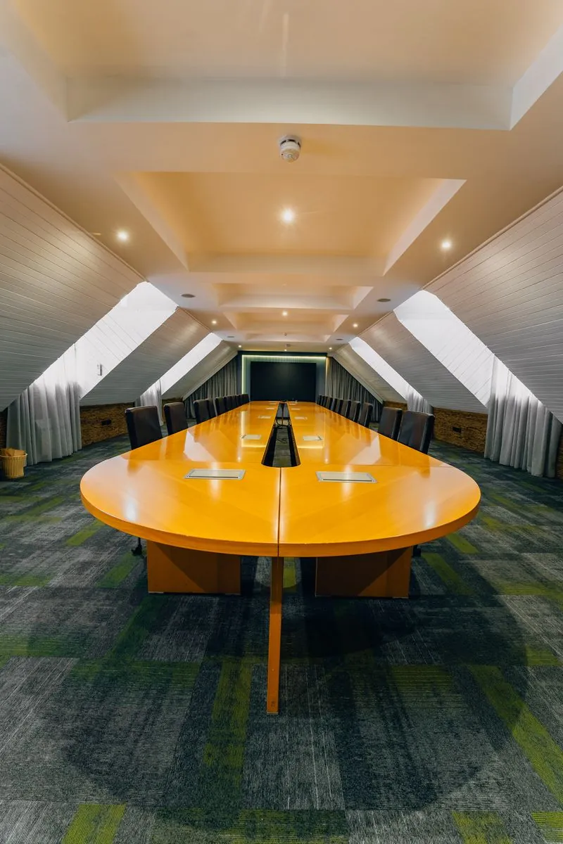 Long polished cherrywood boardroom under pitched ceiling