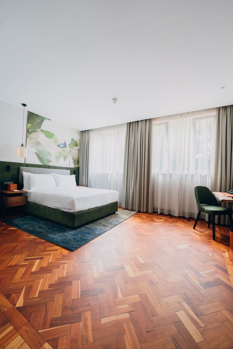 Hotel suite with green bed and parquet floor