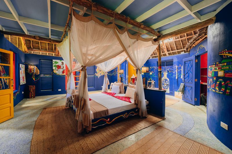 Muralled bedroom with wooden beams and thatch ceiling