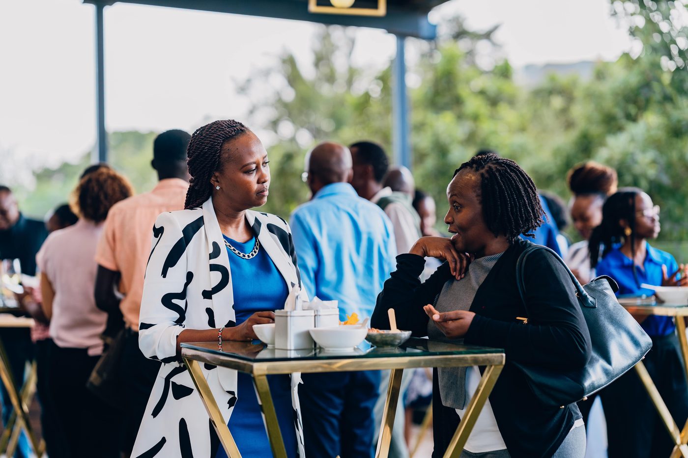 Two women in conversation at a gold-framed table, daylight