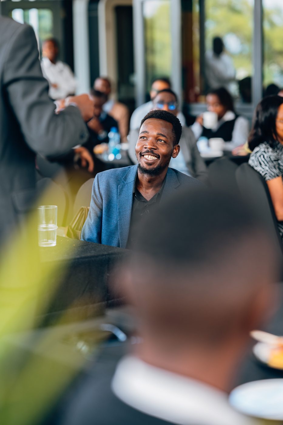 Portrait of a man in a blue blazer smiling warmly during a corporate networking moment
