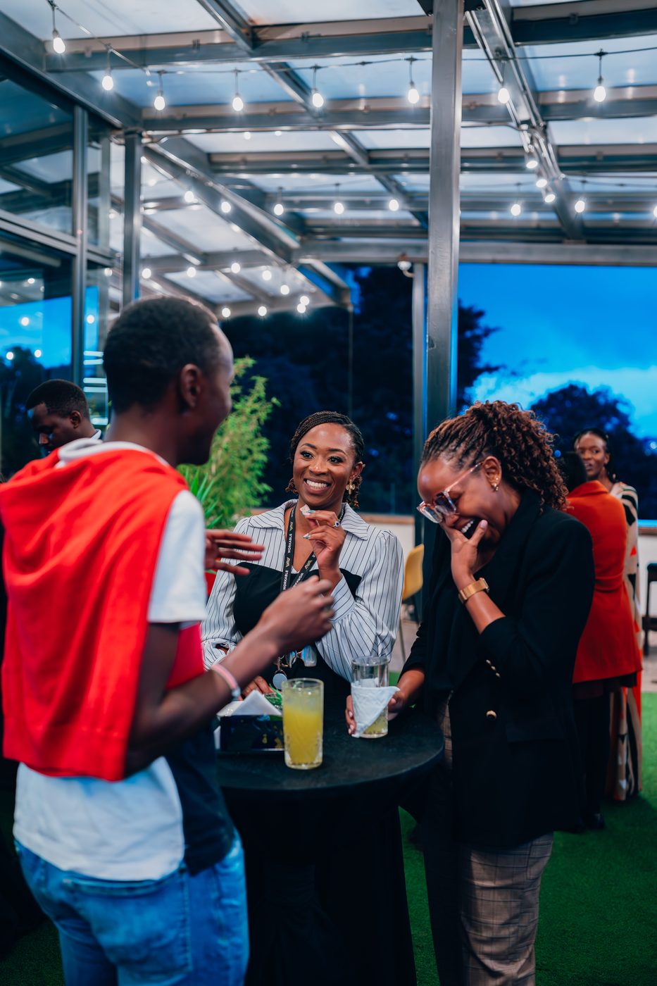 Three women in candid laughter at evening event