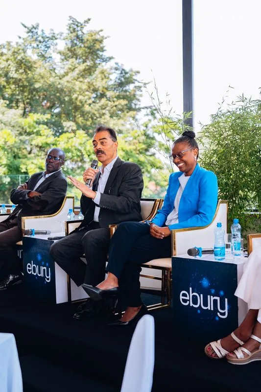 Panellist gesturing while speaking, a colleague in blue listening beside him