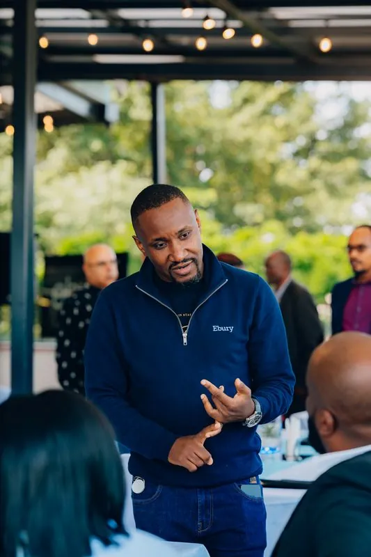 Host in an Ebury zip jacket explaining something to guests