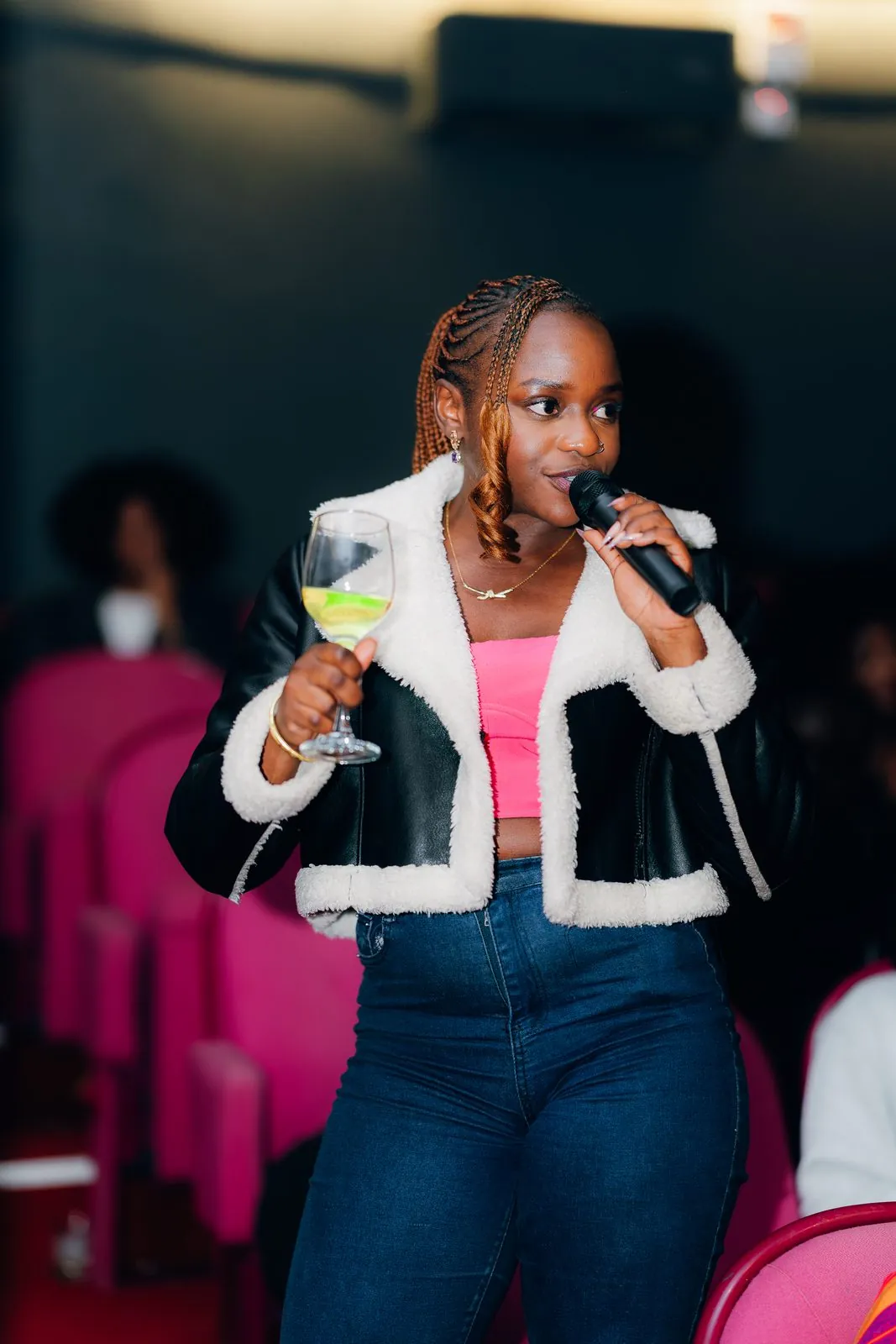 Guest in a shearling jacket asking a question with a microphone and a drink