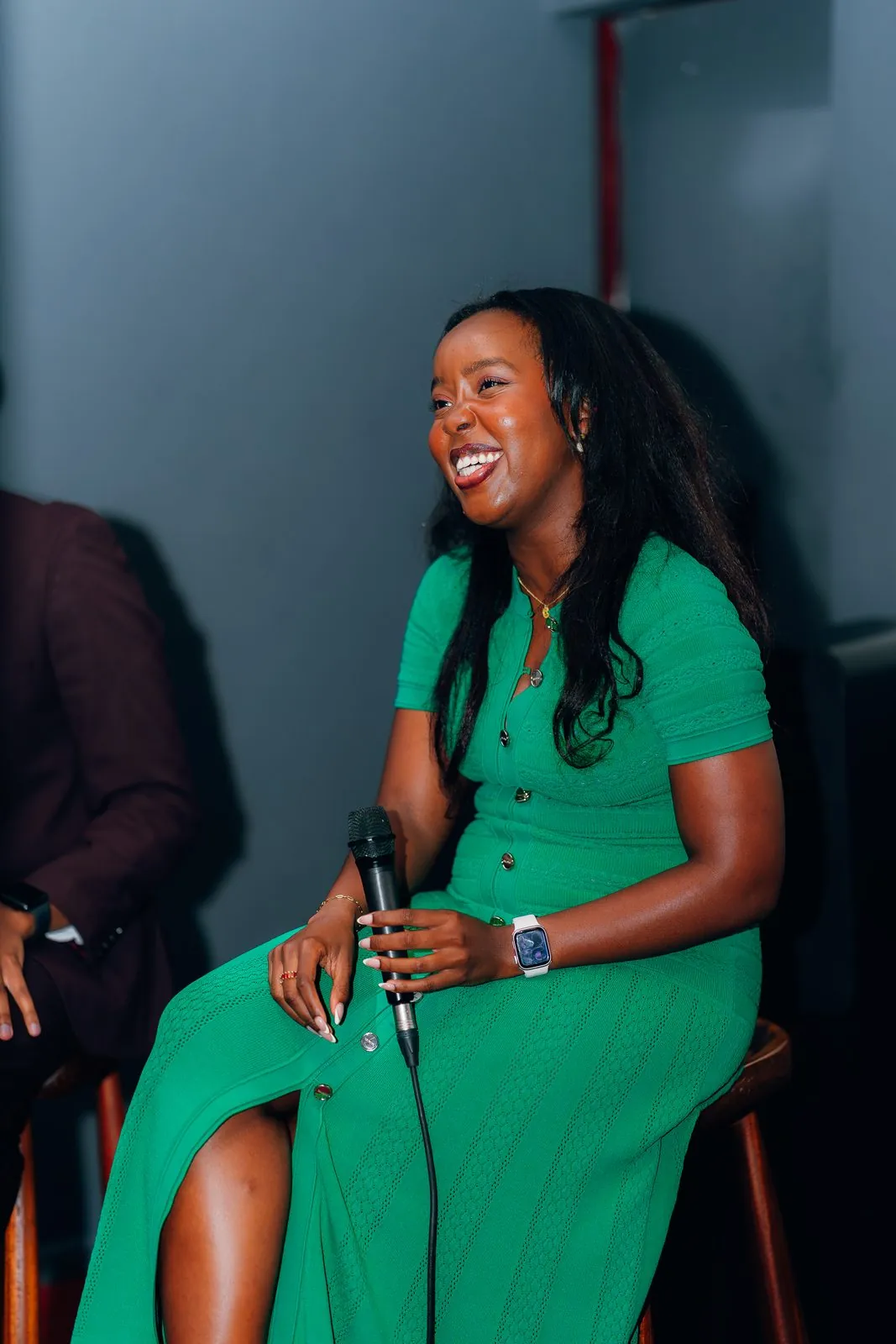 Host in a green dress laughing with a microphone