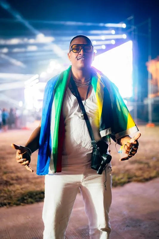 Man wearing a flag as a cape in front of stage lights