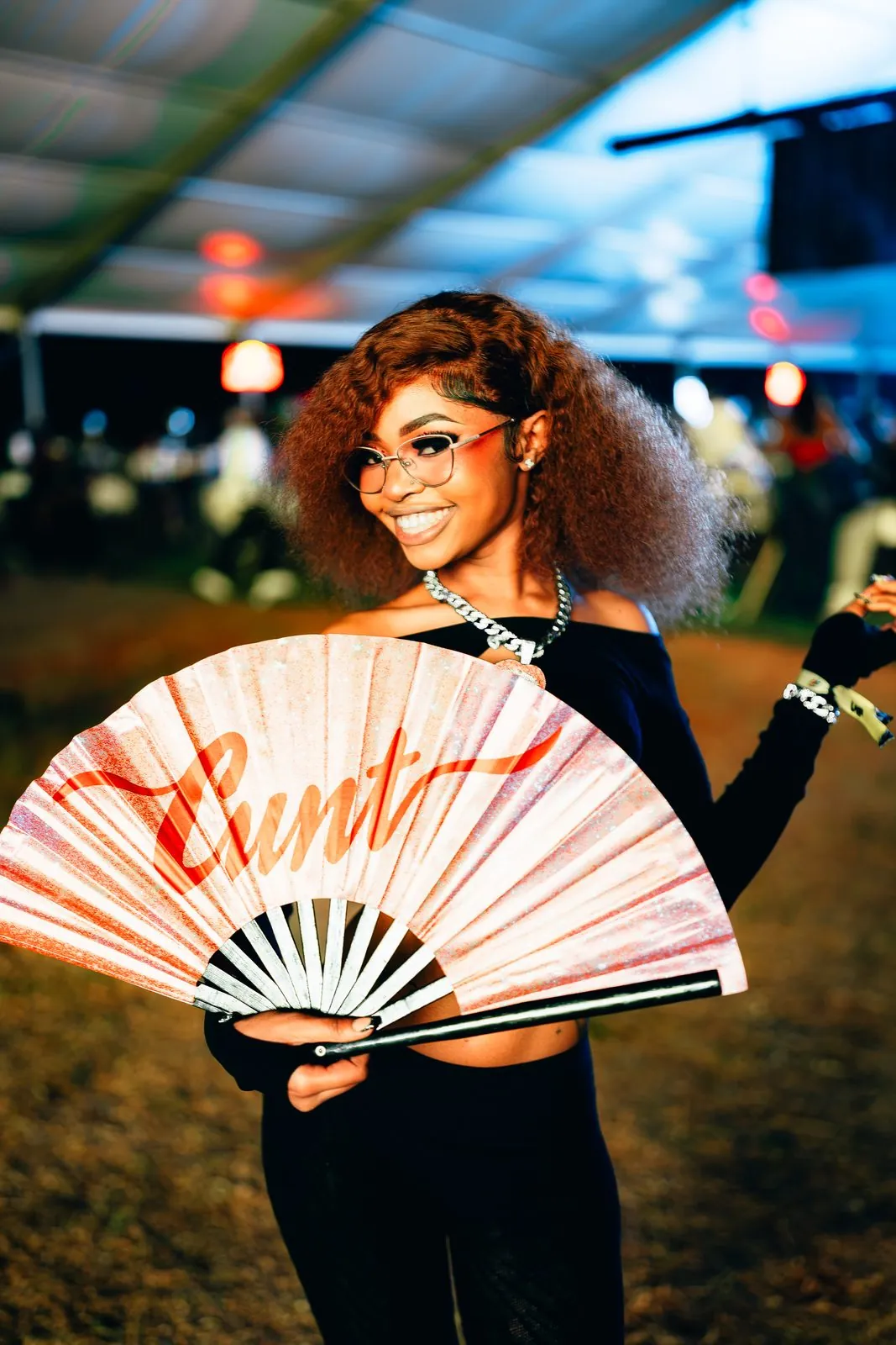 Festival-goer holding a printed hand fan, smiling