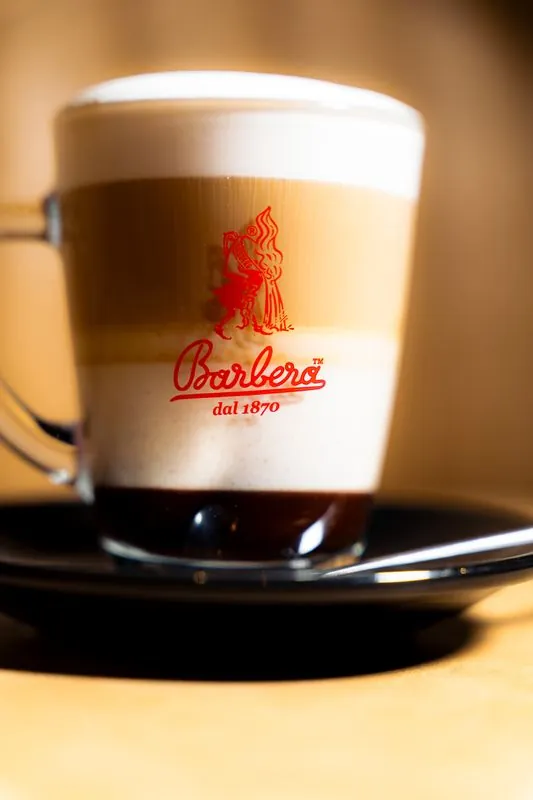 Latte in a branded Barbera glass on a saucer