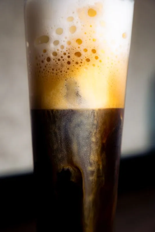 Tall glass of cold brew with foam cascading