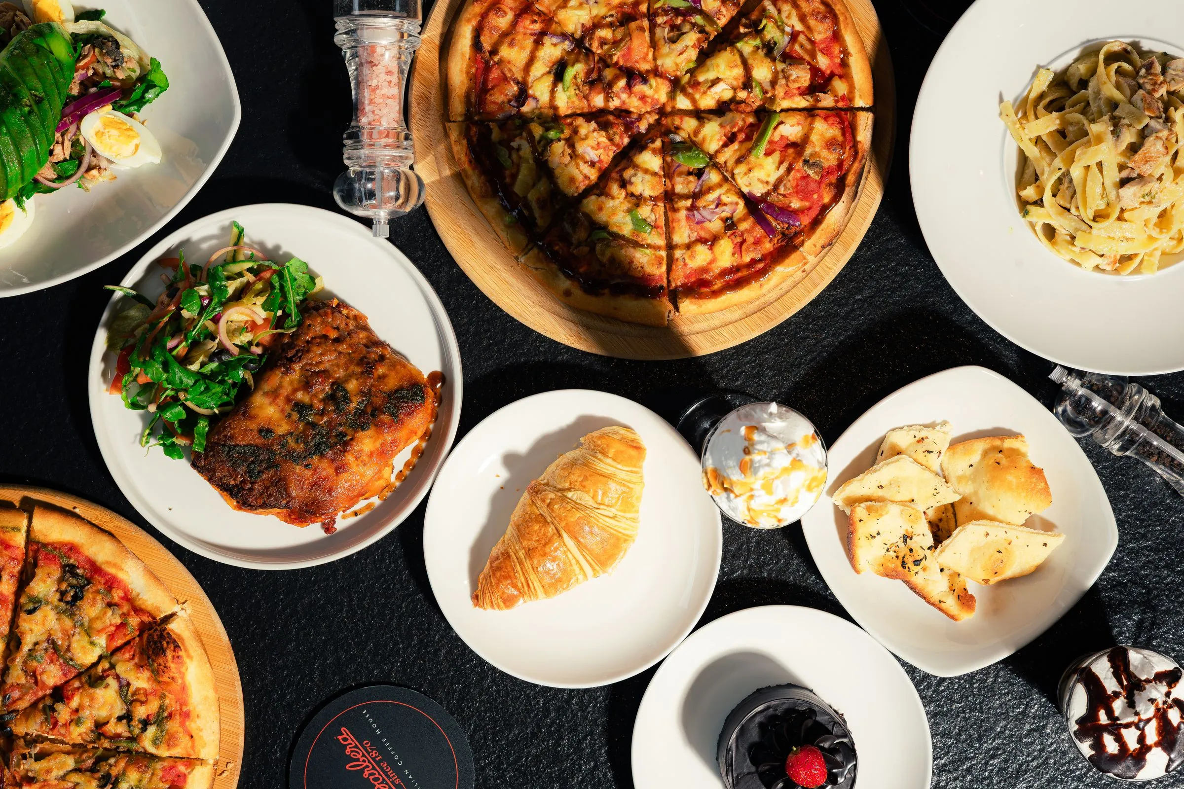 Overhead spread of pizza, pasta, salads and pastries at Café Barbera