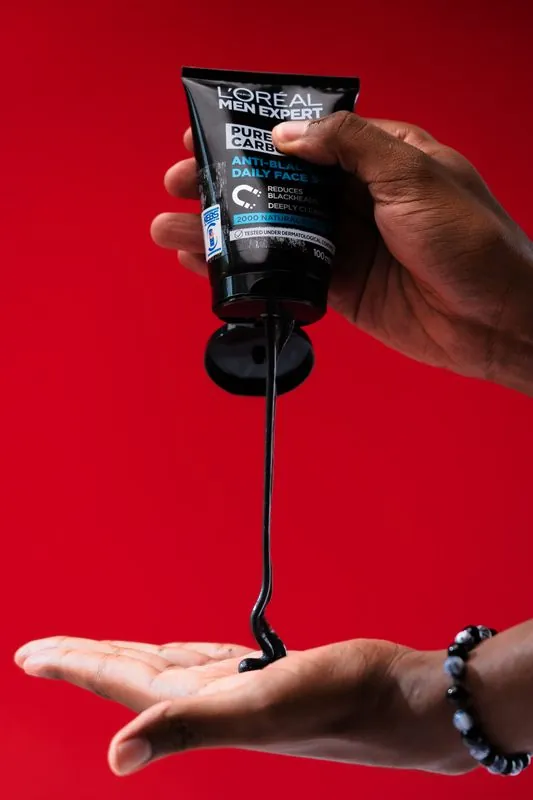 Black charcoal face wash poured from the tube into an open palm