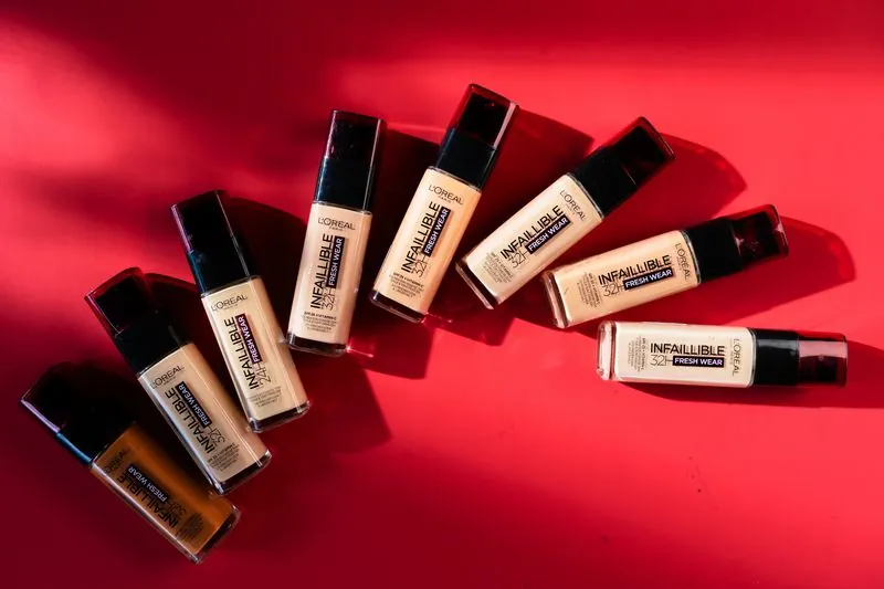 Bottles of Infaillible foundation fanned out in a curve on red