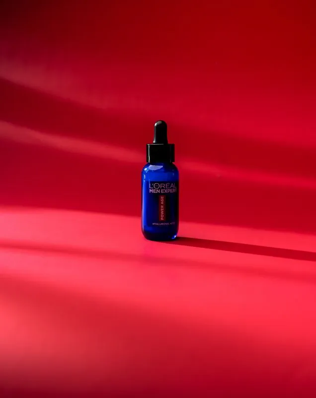 Small blue serum bottle under a single hard light on red