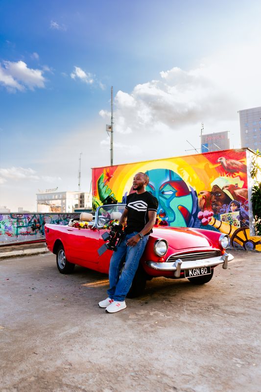 Cinematographer with red vintage car and mural