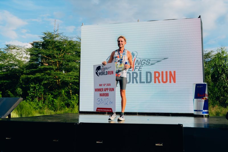 Steffen on the winner's podium holding the Wings for Life sign — 38.02 km