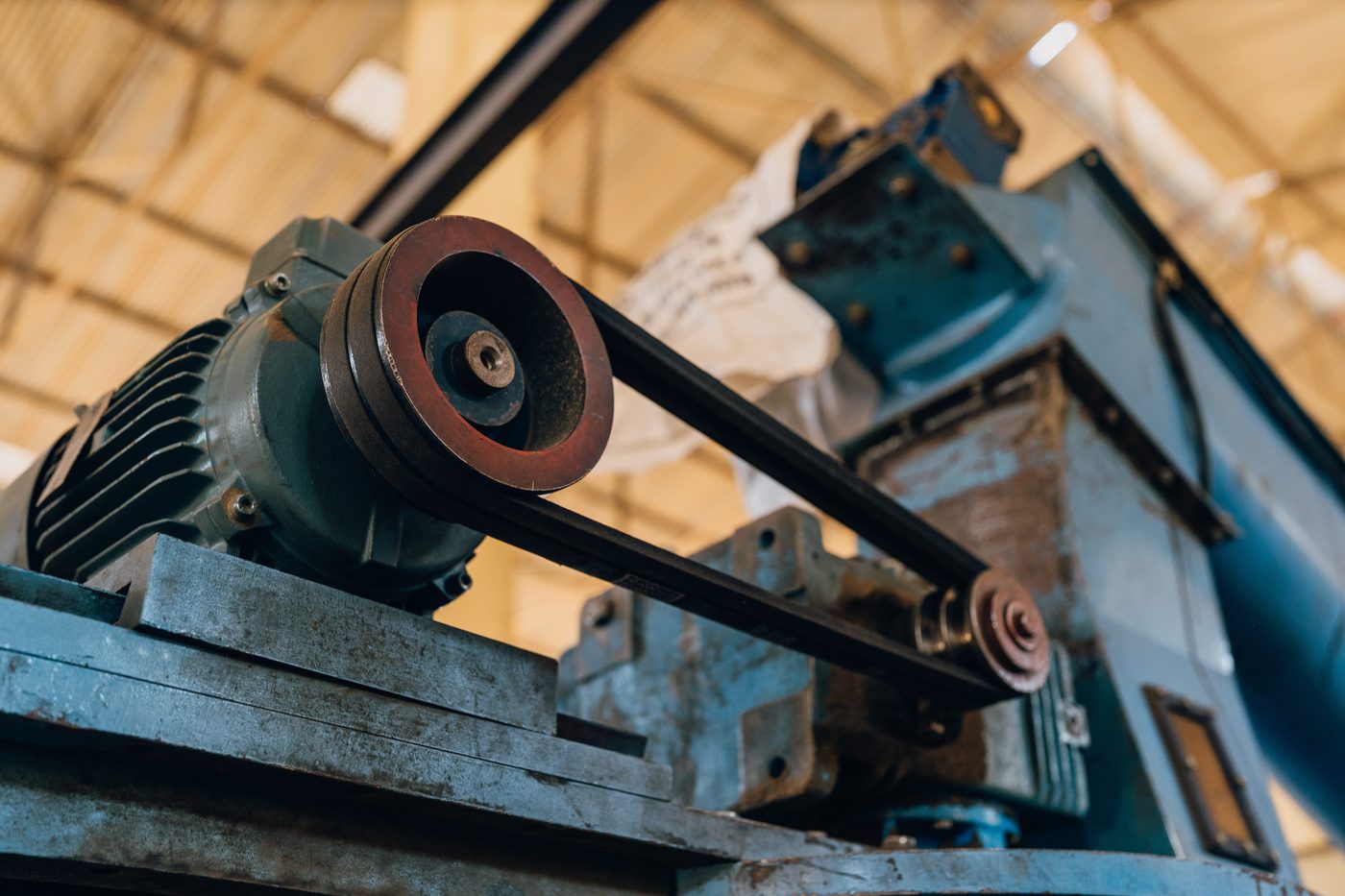 Close detail of a motor pulley and drive belt mounted on a blue machine